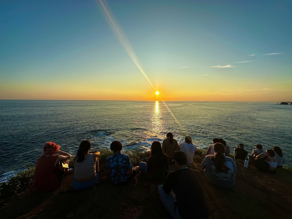 Students watch a sunset over the ocean