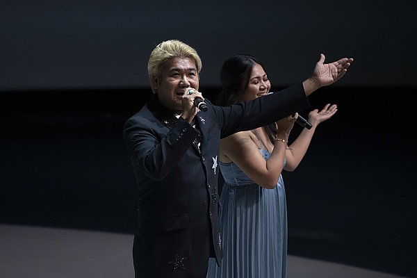 Two people singing into a microphone.