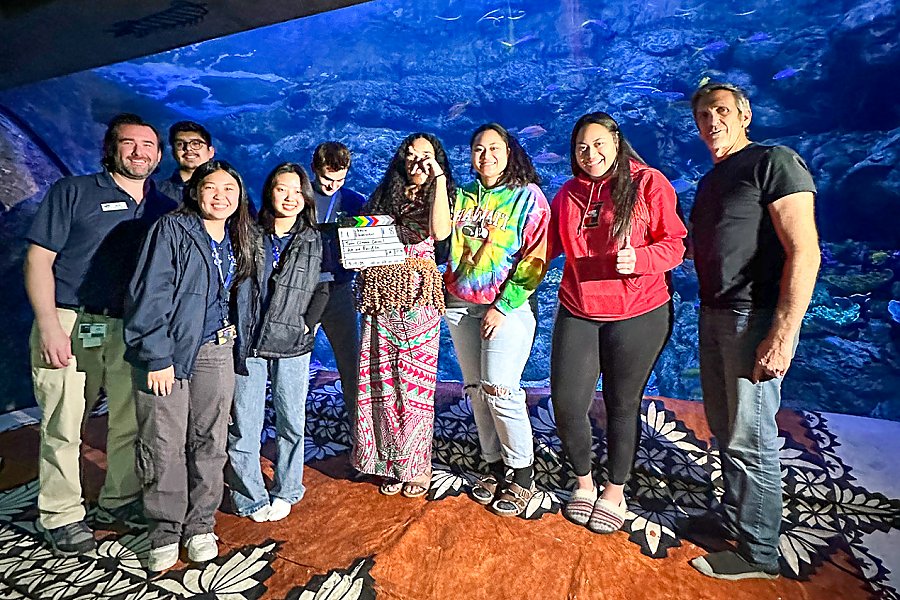 group of teens and adults smiling in front of exhibit