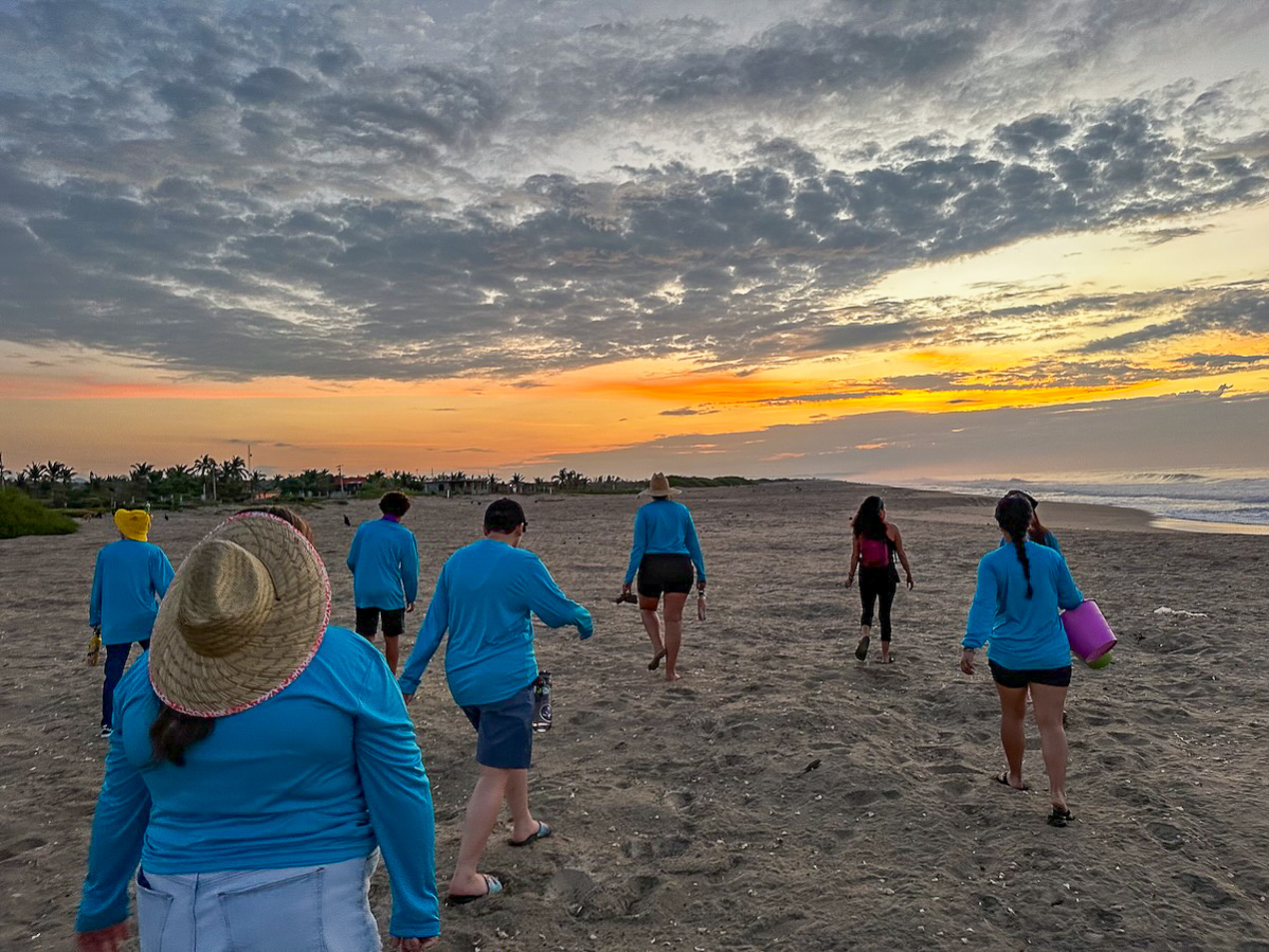 People walking on the beach at sunrise