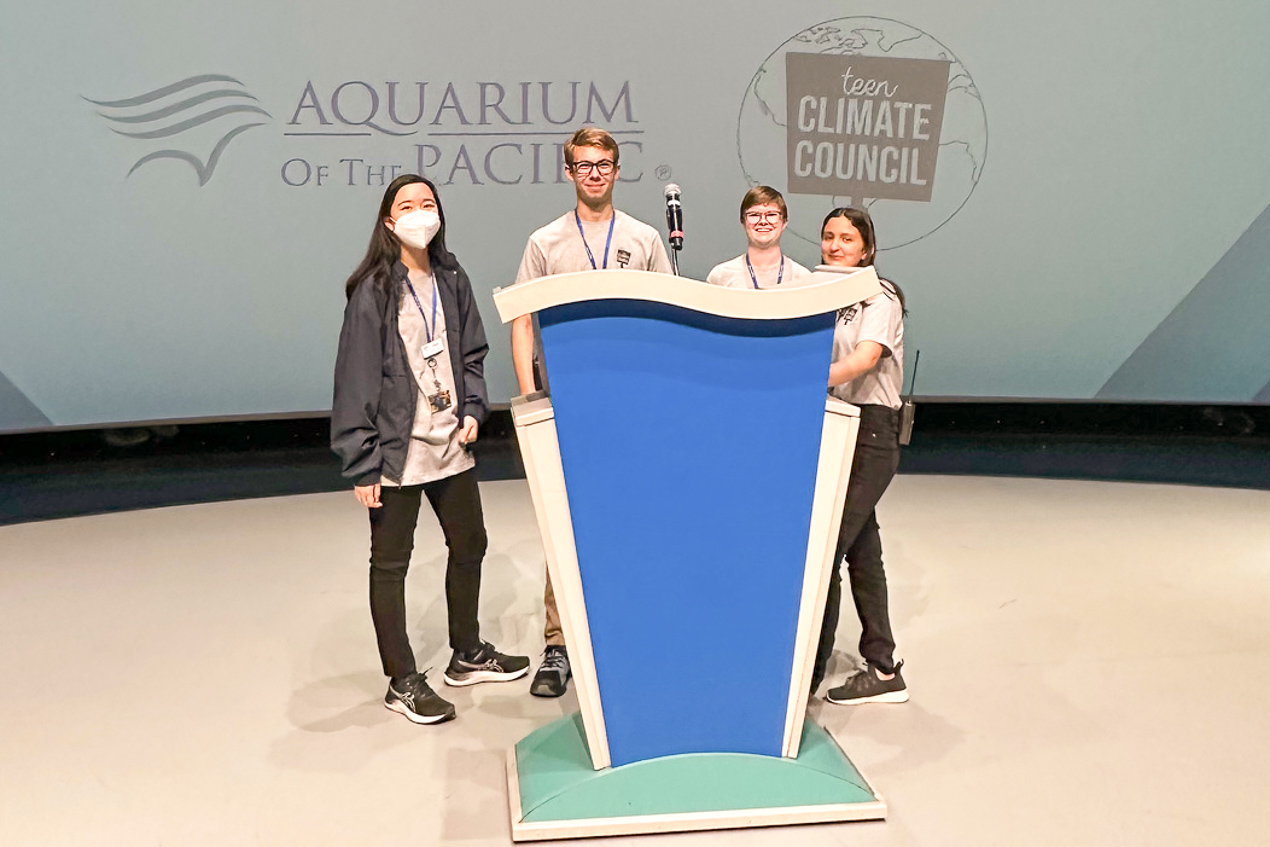 Teens behind a podium smiling